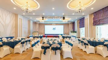 A conference room with round tables, white chairs, and chandeliers.