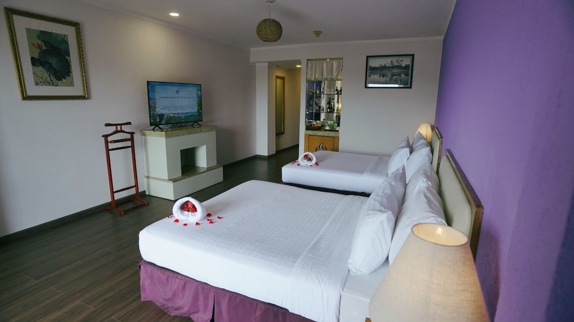 A hotel room with two beds, a TV, a fireplace, and a bathroom visible through an open door.