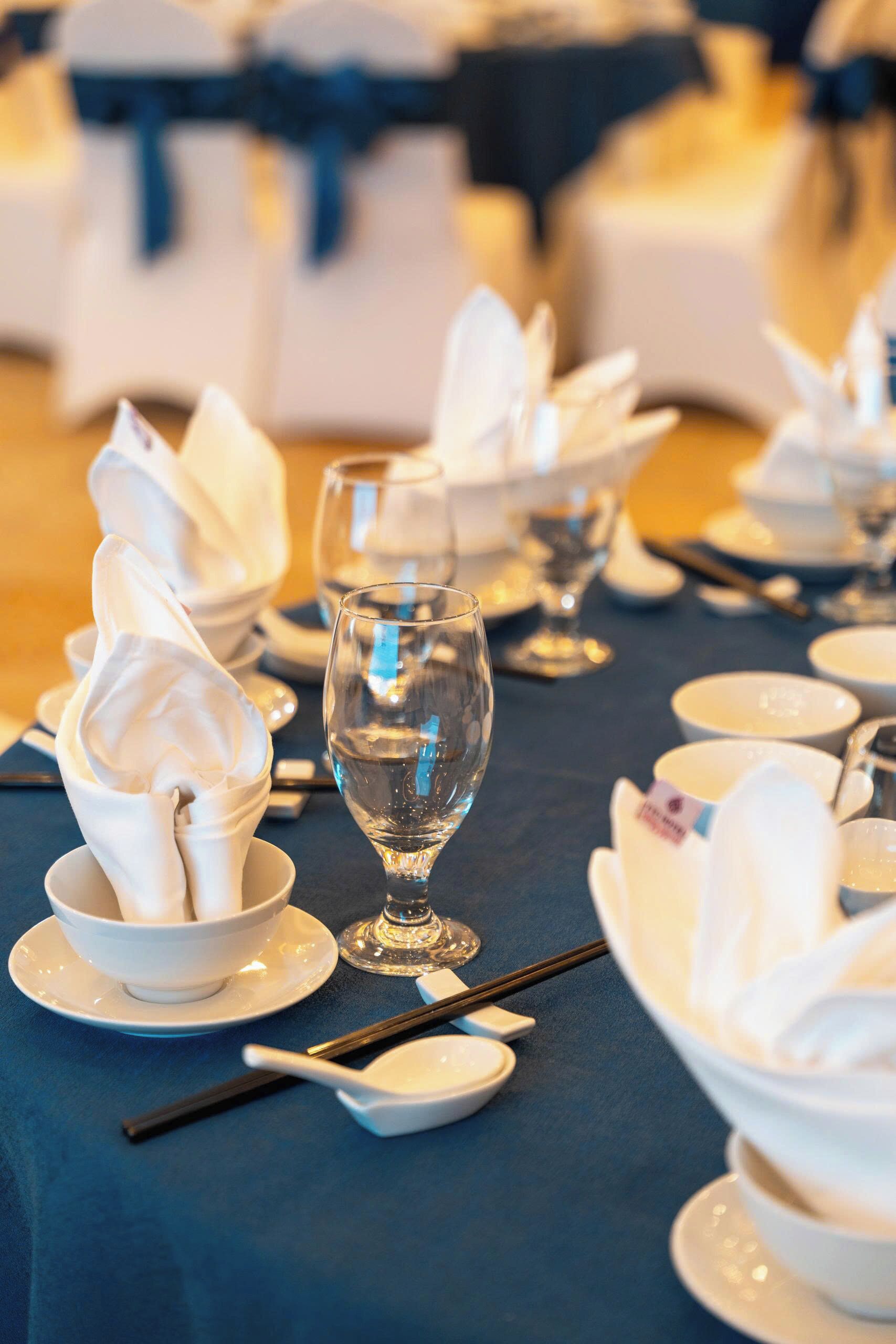 A table set for a formal event with white napkins, clear glassware, and white dishes.