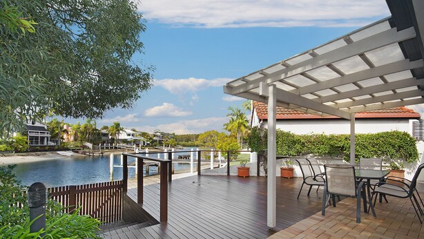 A wooden deck with a pool, outdoor seating, and a view of the water and buildings. - 44 Cooran Court (Noosa Heads)