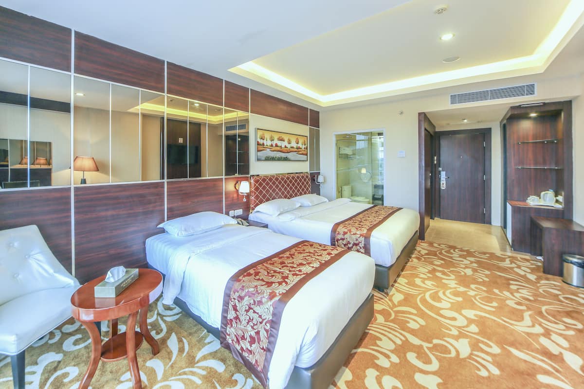 Una habitación de hotel con dos camas, un sofá, una mesita y un espejo grande.