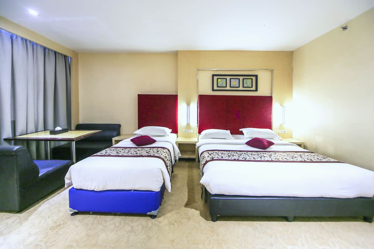 Habitación de hotel con dos camas individuales, un escritorio con silla, un sofá y un ventanal con cortinas.