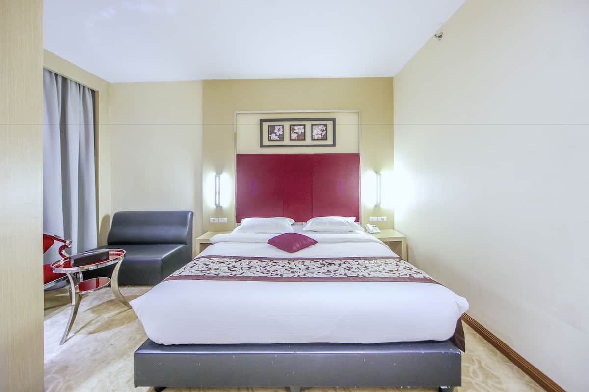 Una habitación de hotel con una cama grande, una silla, un escritorio y una lámpara de escritorio.