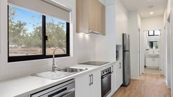 Una cocina moderna con un lavamanos de acero inoxidable, horno empotrado y refrigerador.