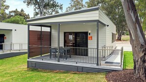 A modern building with a covered outdoor seating area, a door with a number sign, and a tree nearby. - Discovery Parks - Clare (Clare)