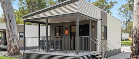 A modern building with a covered porch, outdoor seating, and a number sign indicating room 121.
