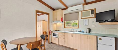 A compact kitchen with wooden cabinets, a microwave, a sink, and a refrigerator.