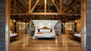 Ein geräumiges Zimmer mit einem großen Bett, Holzbalken und einem Strohdach.