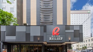 A modern hotel with a prominent 'HOTEL RELIEF' sign, large windows, and a parking area visible in the background. - Hotel Relief Sapporo Susukino (Sapporo)
