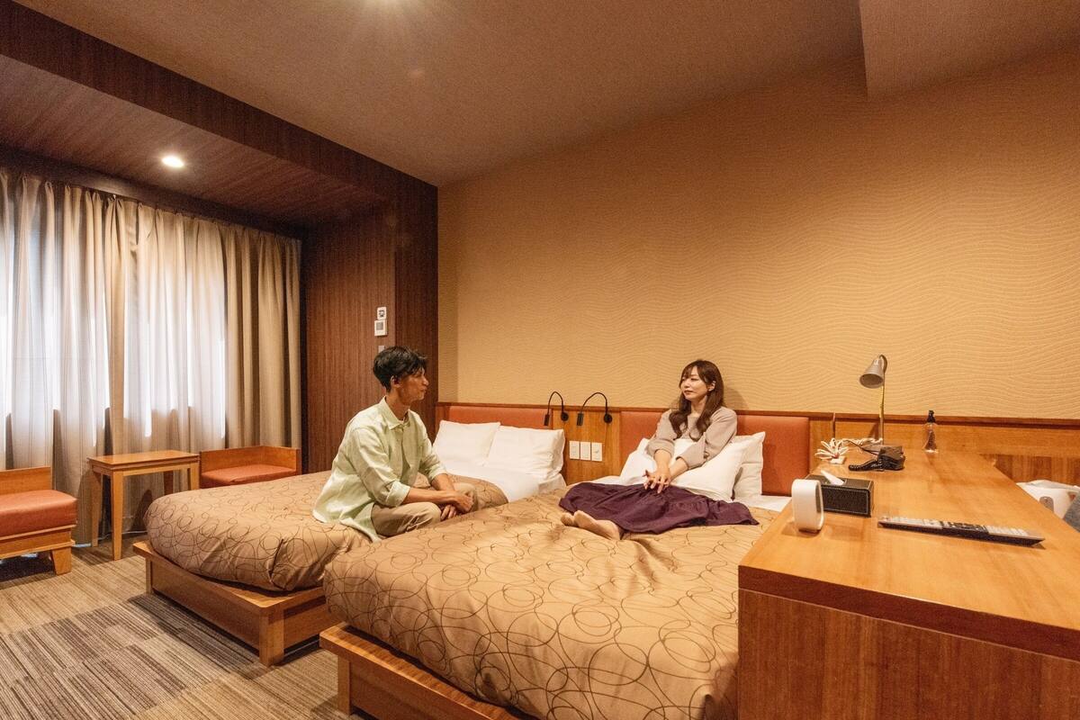 Une chambre d’hôtel avec deux lits, un bureau en bois et une petite table.