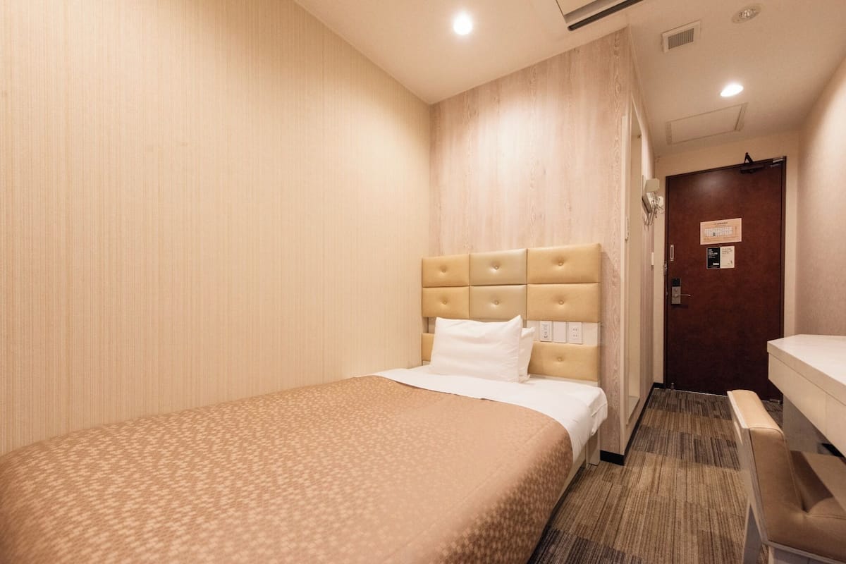 Une chambre d’hôtel avec un lit, une table de chevet et une chaise.