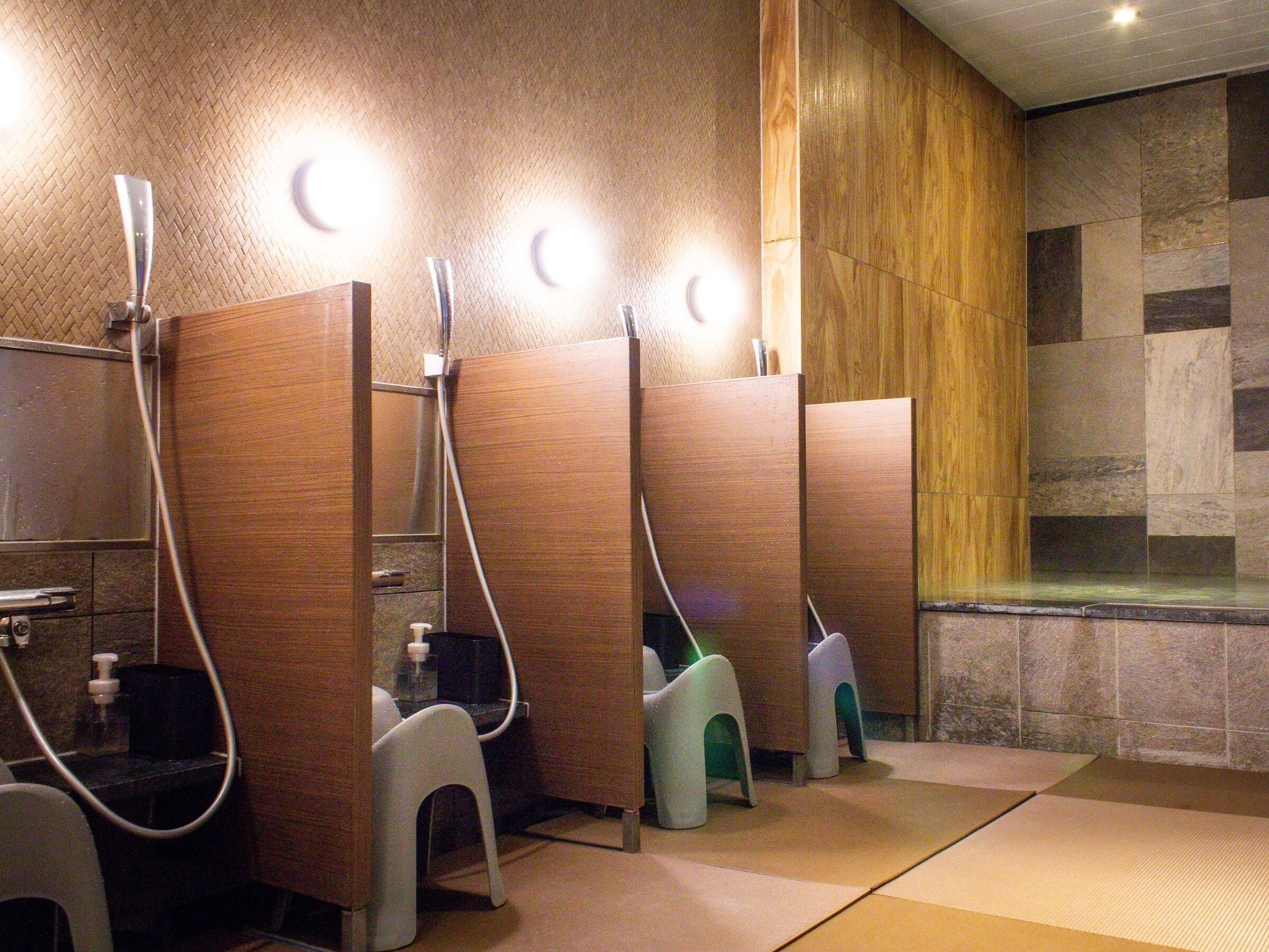 A public restroom with wooden partitions, individual sinks, and a tiled shower area.