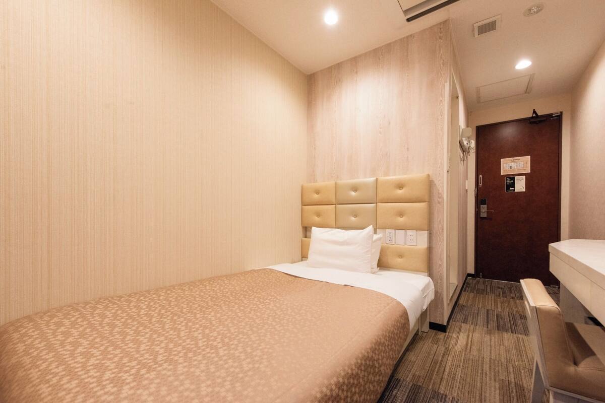 Une chambre d’hôtel avec un lit, une table de chevet et une chaise.