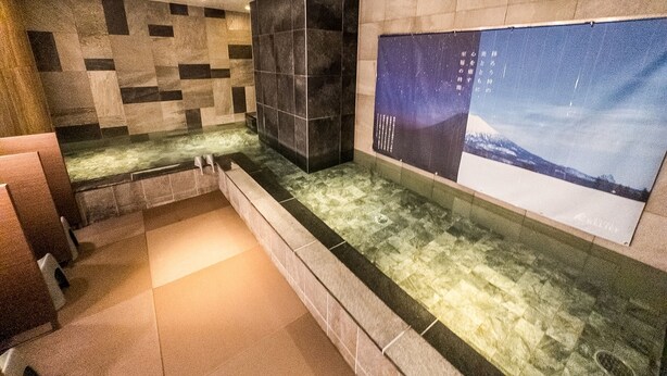 A modern bathroom with a stone wall, a large poster, and a bathtub. - Hotel Relief Sapporo Susukino (Sapporo)