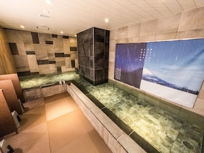 A modern bathroom with a stone wall, a large poster, and a bathtub. - Hotel Relief Sapporo Susukino (Sapporo)