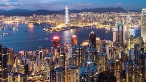 A densely packed urban skyline with high-rise buildings, a harbor with boats, and a clear sky. - Well Yet Guest House (Kowloon)