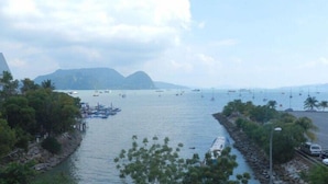 A coastal view with boats, a rocky shoreline, and a mountain in the background. - Geopark Hotel, Kuah Langkawi (Langkawi)