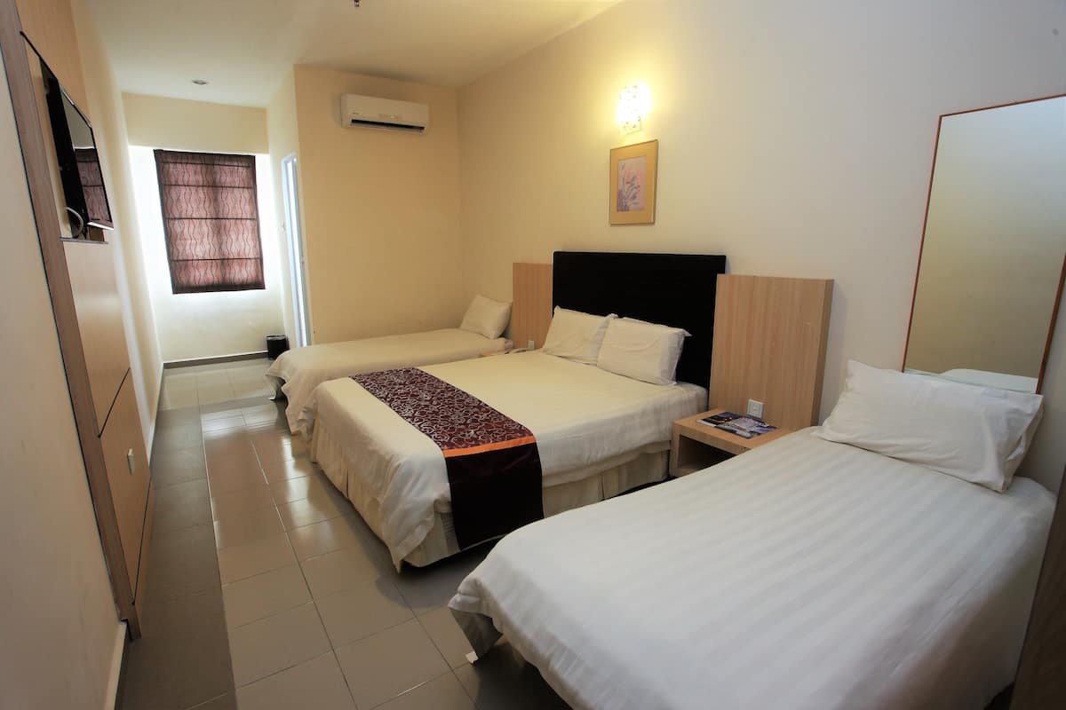 Une chambre d’hôtel avec deux lits, une table de chevet, une commode, un climatiseur fixé au mur et une fenêtre avec un rideau.