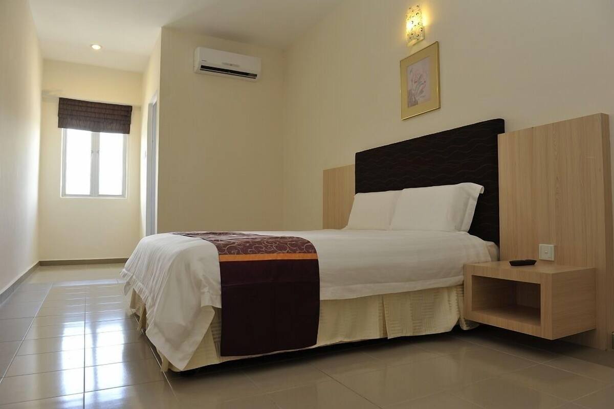Une chambre bien rangée, avec un lit, une table de chevet et un climatiseur fixé au mur.