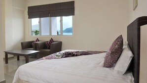 A bedroom with a bed, a sofa, a table, and a window with a view of the outdoors. - Geopark Hotel, Kuah Langkawi (Langkawi)