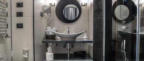 A modern bathroom with a large mirror, a vessel sink, and a glass-enclosed shower.