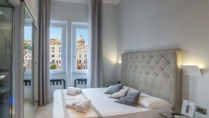 A hotel room with a large bed, a glass table, a view of a cityscape, and a Sky remote control on the wall. - Pantheon Caesar Relais (Rome)