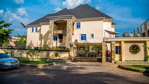 A two-story house with a stone facade, a balcony, and a gated entrance. - Fritz Apartments and Suites (Abuja)