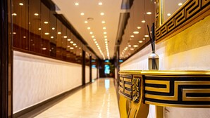 A corridor with a reflective floor, a decorative golden column, and a modern ceiling with recessed lighting. - Fritz Apartments and Suites (Abuja)