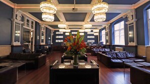 A spacious lobby with dark blue walls, multiple seating areas, and large chandeliers. - Morgans Hotel (Swansea)