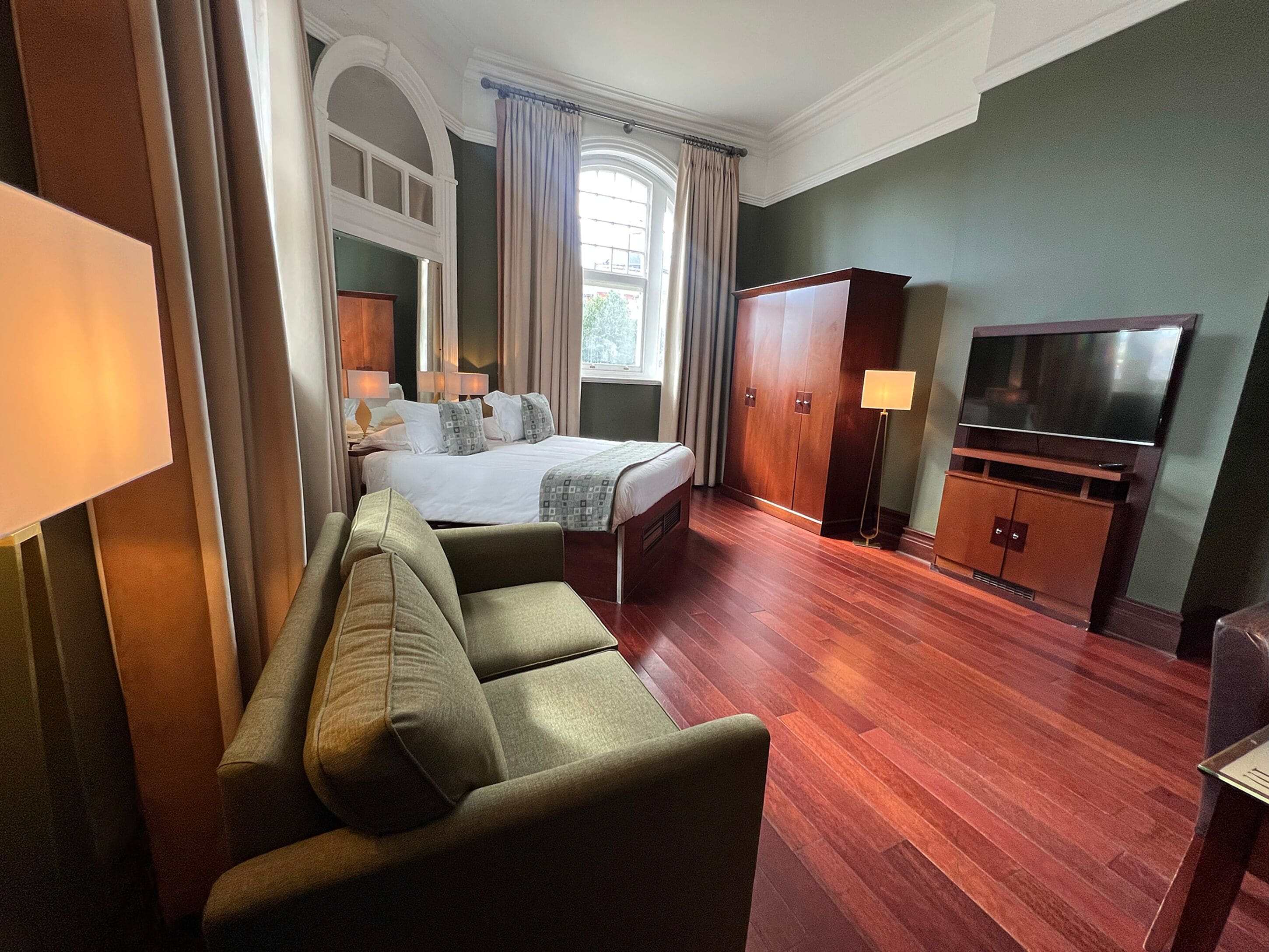 Una habitación de hotel con cama, sofá, televisión y armario.