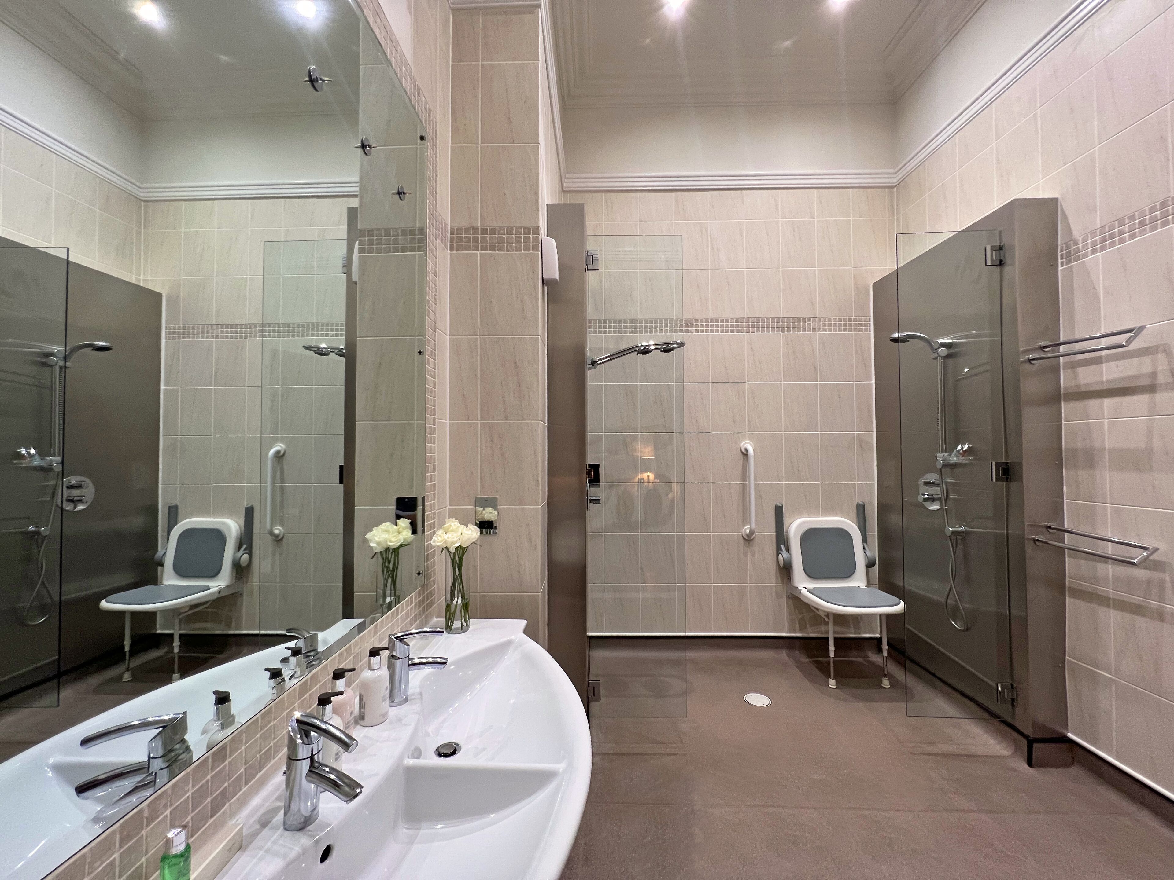 Une salle de bain moderne avec un grand lavabo, des miroirs et un espace douche.