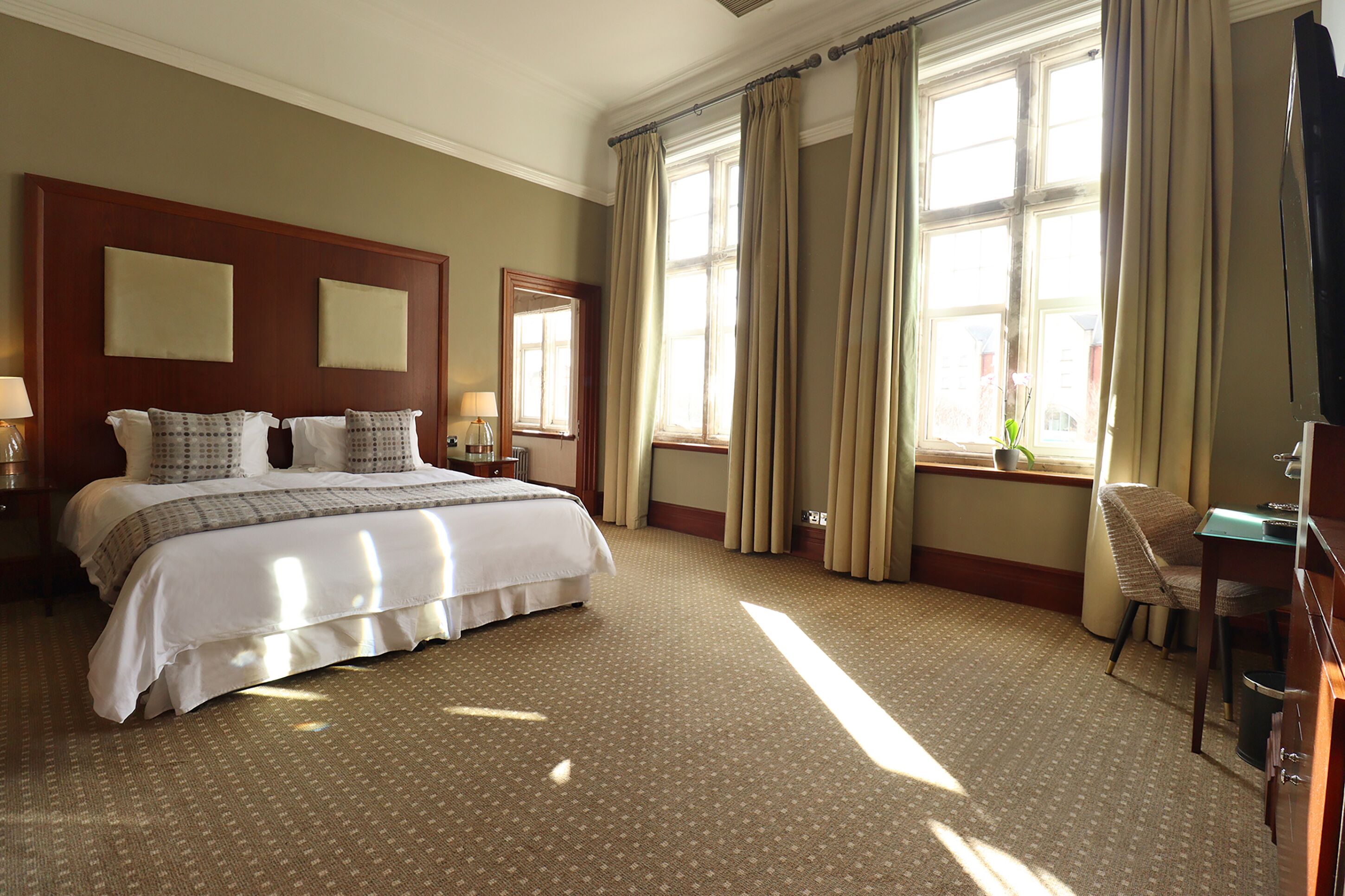 A hotel room with a large bed, a desk, and a chair.