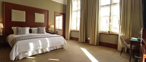 A hotel room with a large bed, a desk, and a chair.