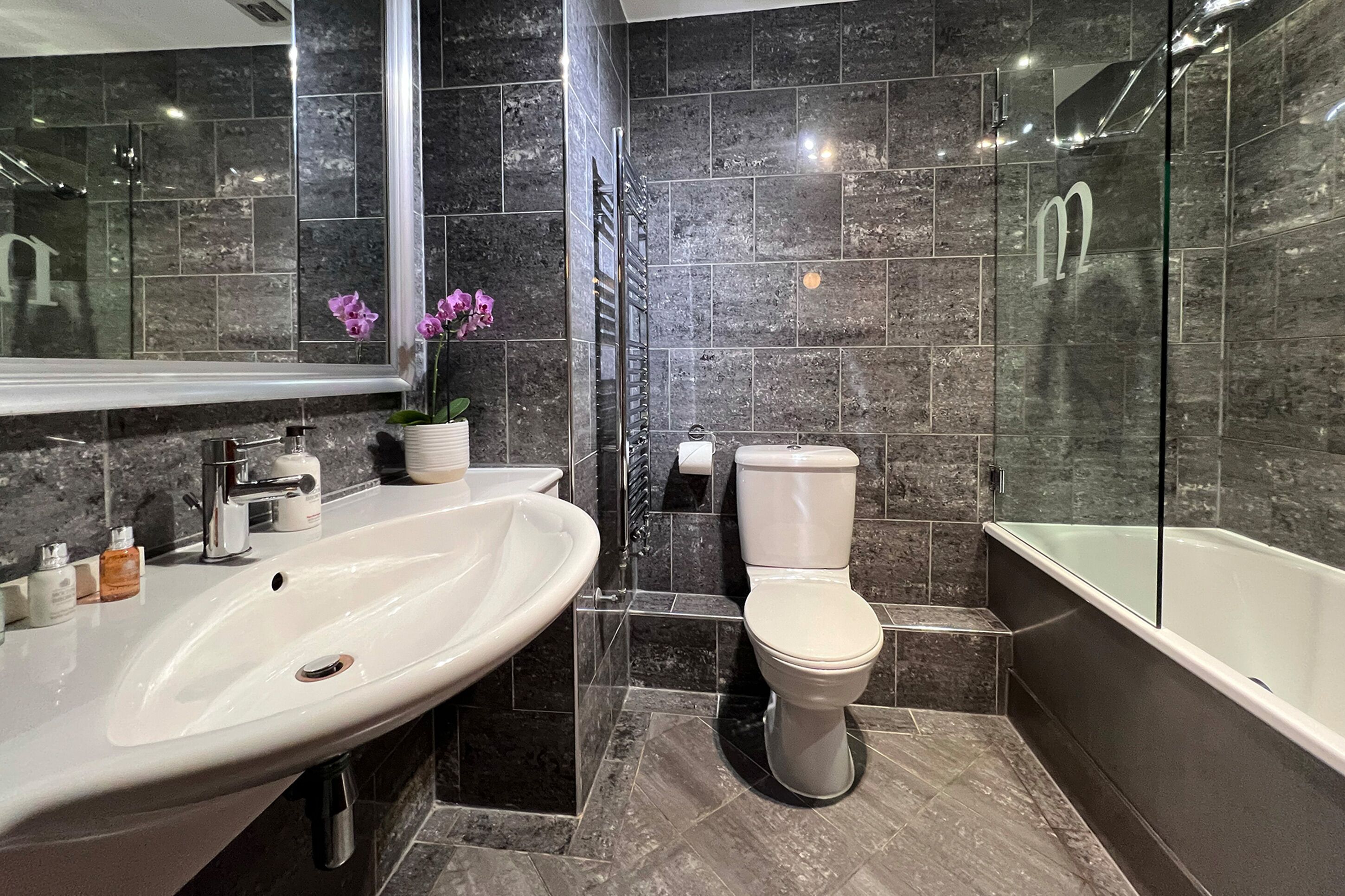 A modern bathroom with a large white sink, a toilet, and a bathtub.