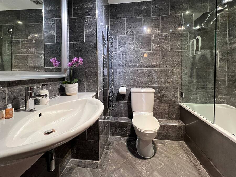 A modern bathroom with a large white sink, a toilet, and a bathtub.