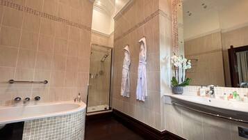 A modern bathroom with a large bathtub, a walk-in shower, and a vanity with a mirror.