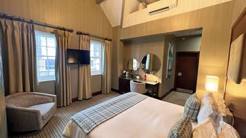 Una habitación de hotel con una cama grande, una silla, un escritorio con espejo, un televisor de pantalla plana y una ventana con cortinas.