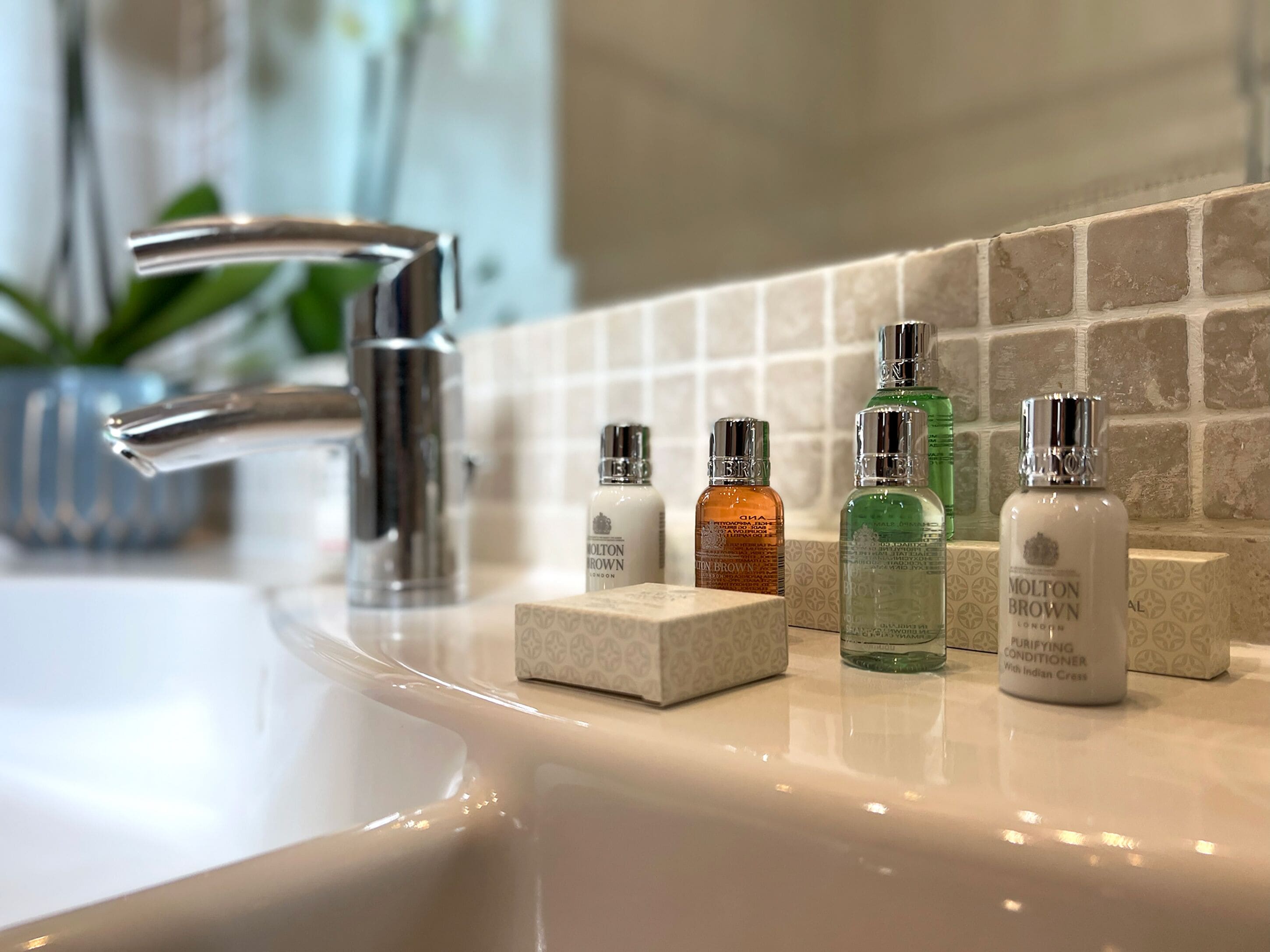 A bathroom sink with a modern faucet and three bottles of toiletries on the counter.