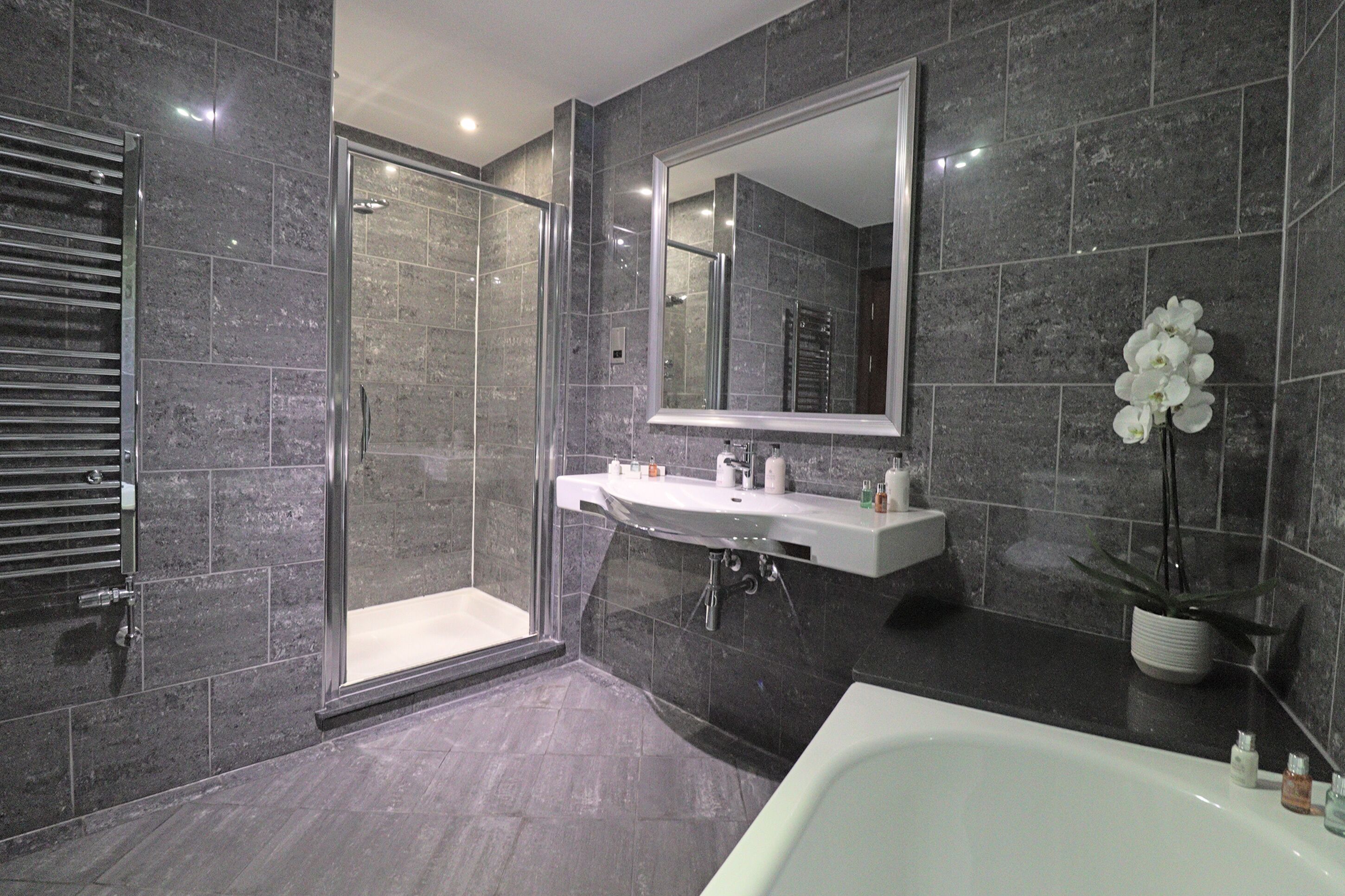 A modern bathroom with a glass shower enclosure, a white sink, and a large mirror.