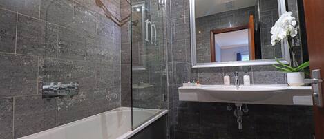 A modern bathroom with a glass-enclosed shower, a freestanding bathtub, and a vanity with a mirror and sink.