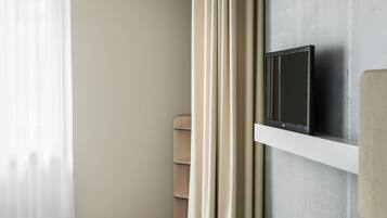 A hotel room with a bed, a TV mounted on the wall, a pair of shoes, and a bag.