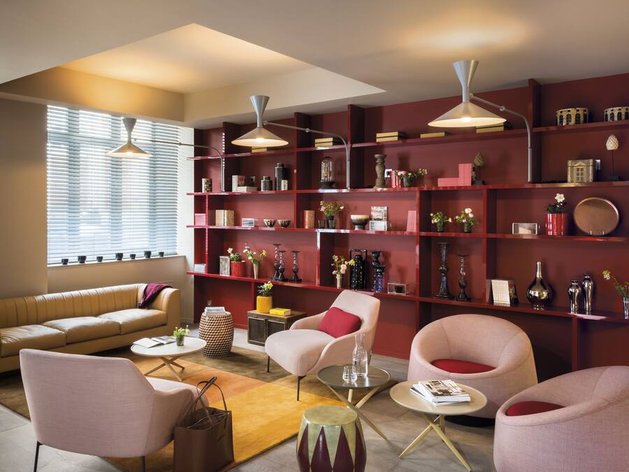 A modern living room with a sofa, armchairs, a coffee table, and a bookshelf filled with decorative items.