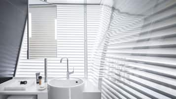 Un baño moderno con lavamanos, espejo y toallero blancos.