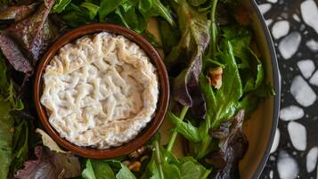 A bowl of salad with a creamy dip on a black and white speckled surface.