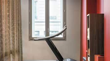 Habitación con una cinta de correr, una pelota de ejercicios grande y una bolsa roja en el suelo.