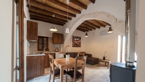 Una cocina rústica con armarios de madera, una mesa de comedor con sillas y un piso de piedra.