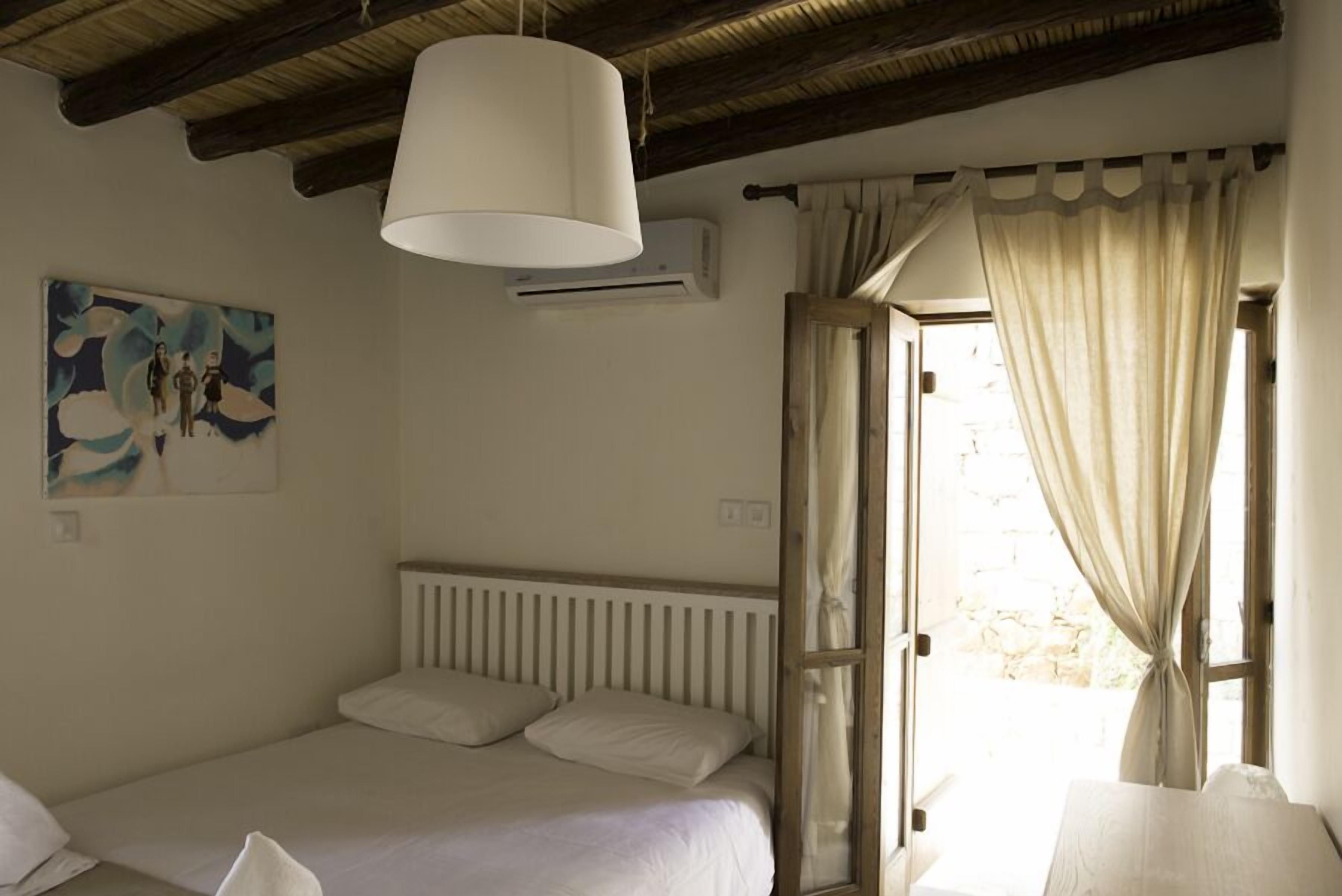 Ein Schlafzimmer mit einem Bett, einer Pendelleuchte, einer Heizung und einem Fenster mit Vorhängen.