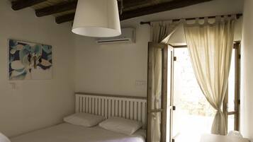 Ein Schlafzimmer mit einem Bett, einer Pendelleuchte, einer Heizung und einem Fenster mit Vorhängen.