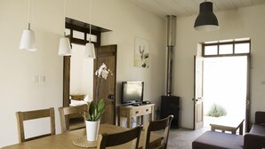 Una sala de estar acogedora con una mesa de comedor de madera, sillas, un sofá, un televisor y una chimenea.