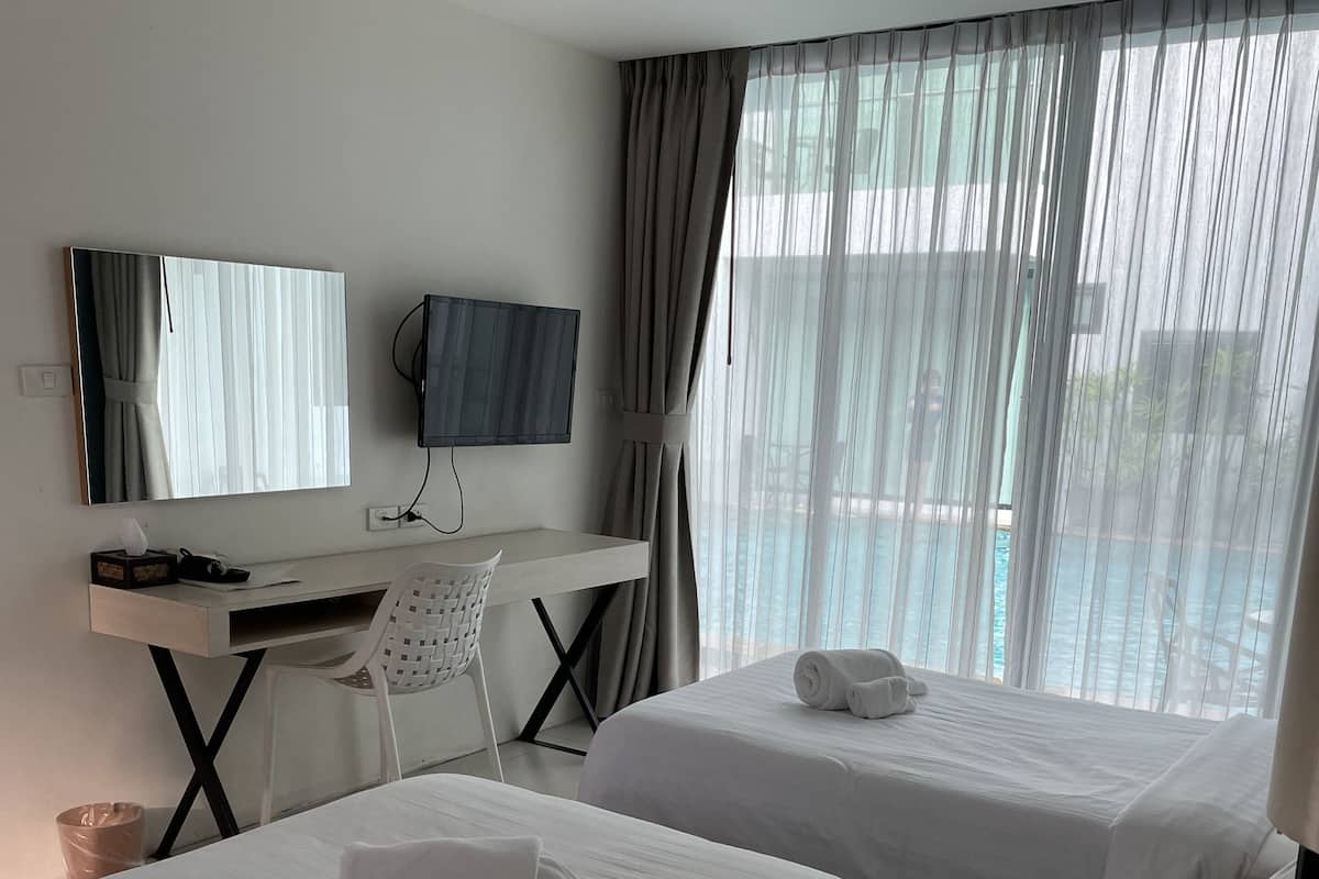 Habitación de hotel con dos camas, un escritorio, una silla, un televisor y vista al mar.